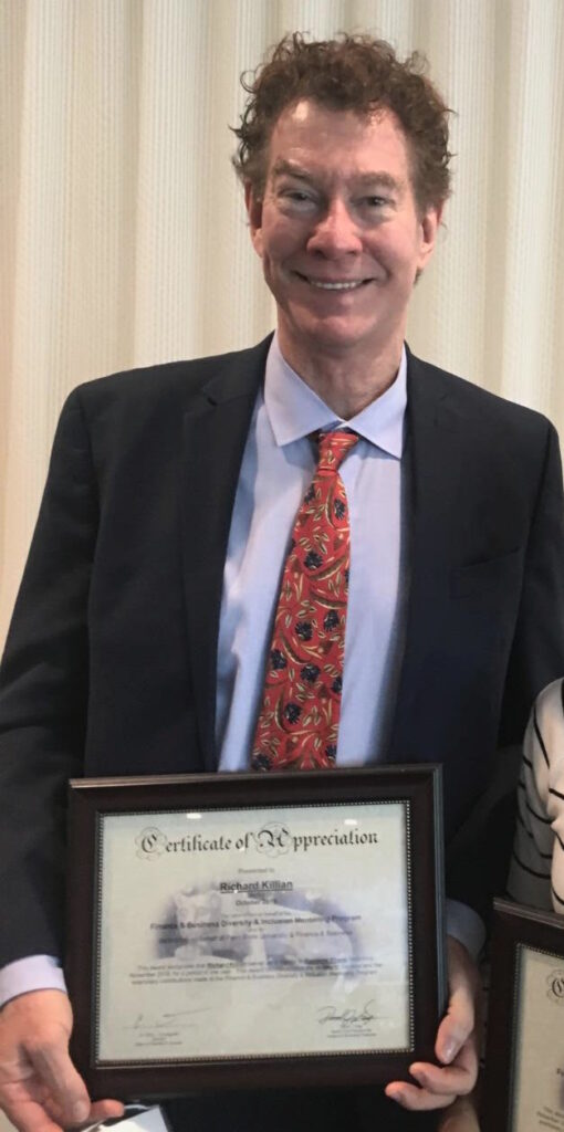 Photo of Richard Killian. Richard Killian’s background in university research accounting and sponsored research finance supports effective grant management, accounts receivable aging analysis, sponsor billing, and award closeout. Photo of Richard Killian winning an award from Penn State (PSU). Richard Killian is wearing a tie and suit. 